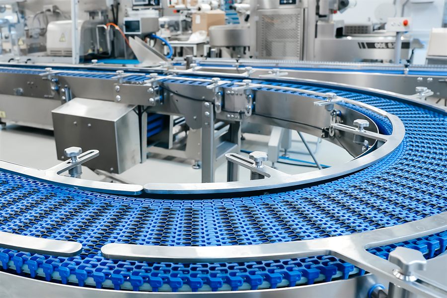 Long industrial belt conveyor running through a plant